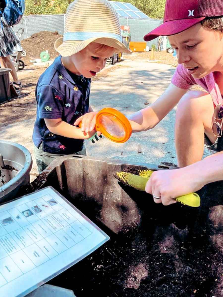 Child exploring plants with a magnifying glass at Governors Island Urban Farm – a hands-on educational activity for kids.