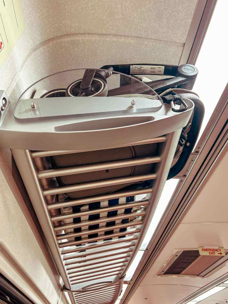 Cabin approved stroller folded neatly and stored in the luggage rack on a train.