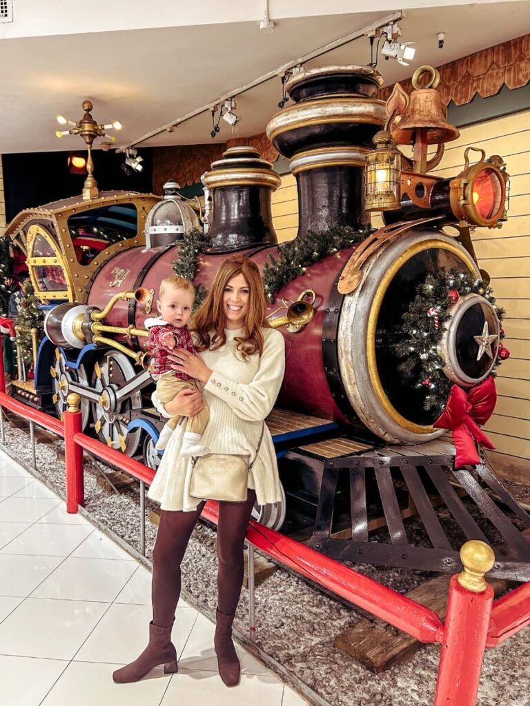 Mum in the City and her baby by the Christmas train outside Macy's Santaland NYC