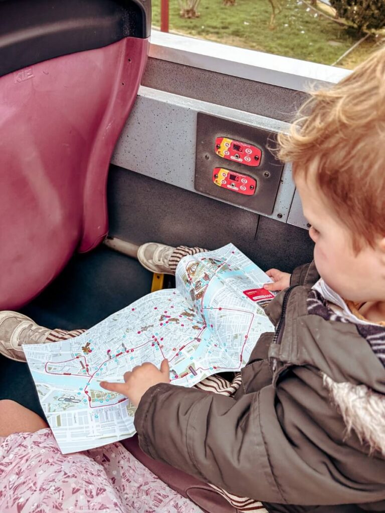Toddler looking at the route map on a City Sightseeing bus in Seville. A great way to get around Seville with kids.