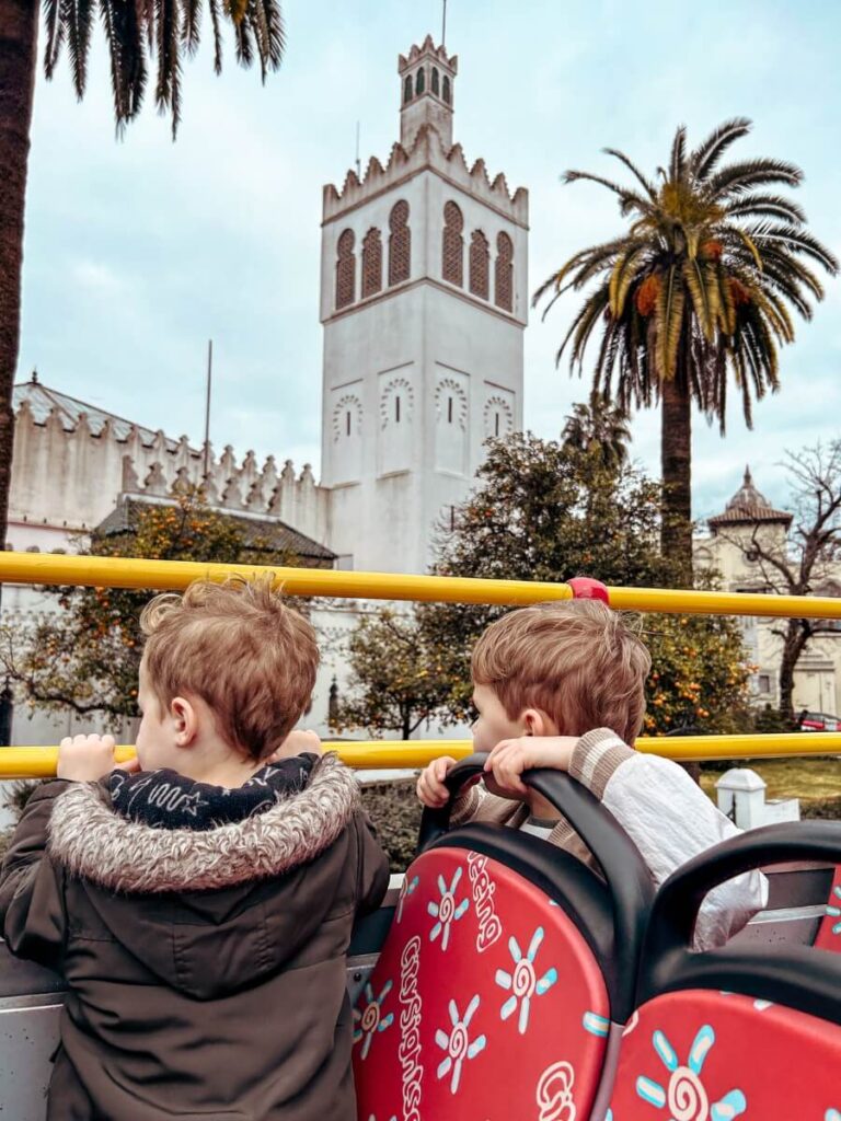Kids looking out at the view from the tip deck of a City Sightseeing bus in Seville, Spain.