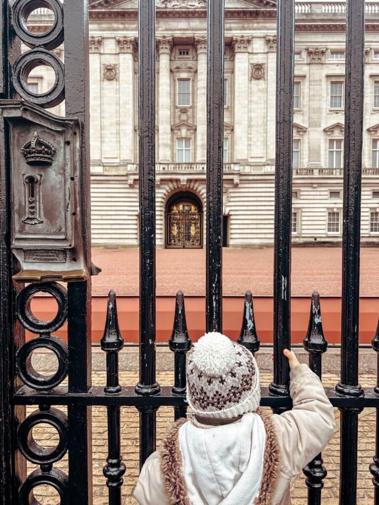 Child looking through the gates of Buckingham Palace in Westminster, one of the best areas in London to stay with kids.