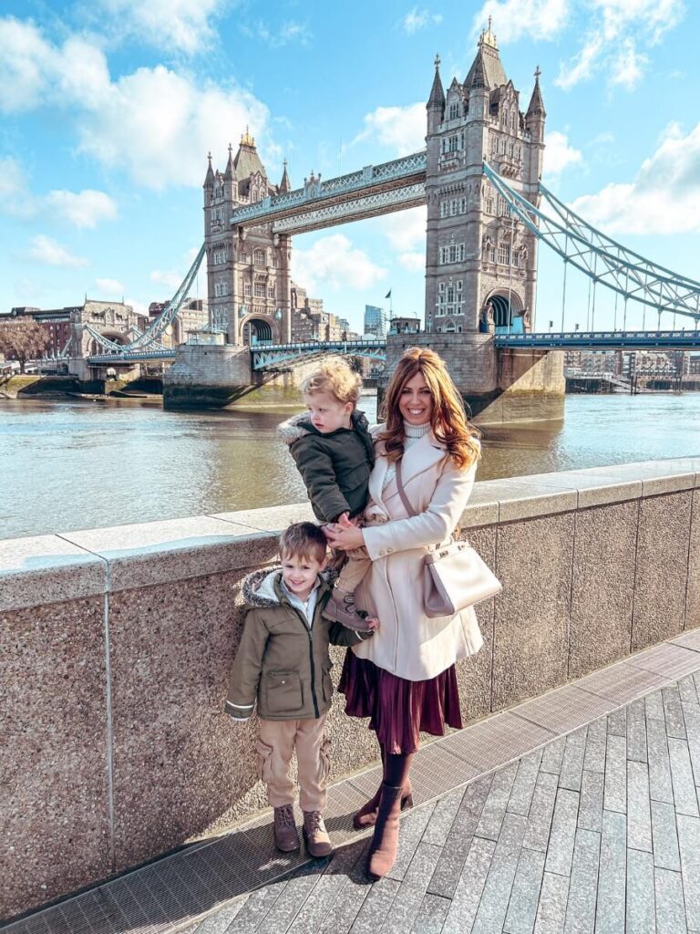 Family standing in front of Tower Bridge, a great area to stay in London with kids.
