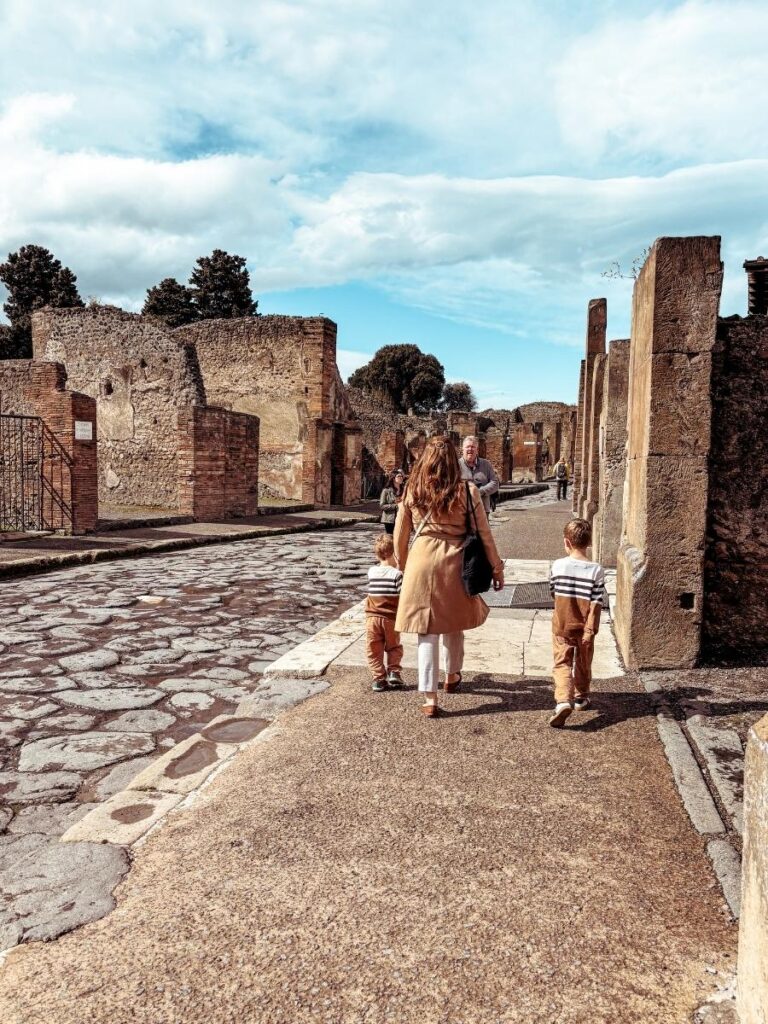 Kids running in the ruins of Pompeii, Italy on a family day trip from Naples.