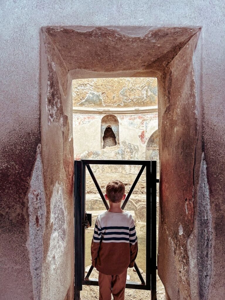 Child looking in to the historic Roman Baths at Pompeii.