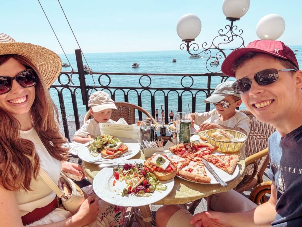 Family eating lunch with a view of the sea, one of the best things to do in Amalfi Town. 