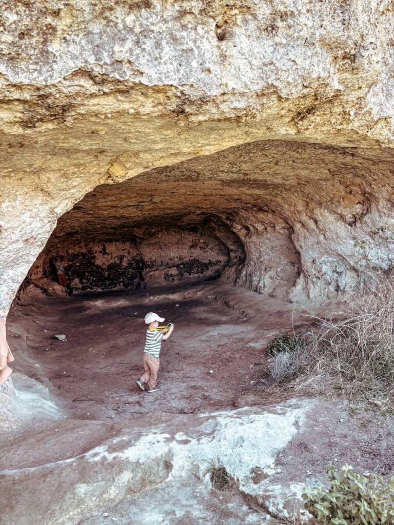 Child exploring the ancient caves at the top of the Belvedere Murgia Timone hike.