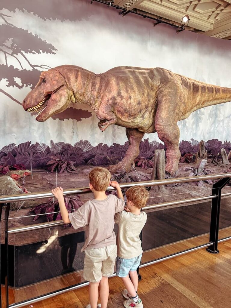 Children looking at dinosaurs in the Natural History museum. One of the top indoor activities in London for a rainy day.